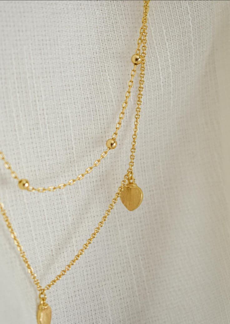 Gold necklace detail: delicate chain, beaded accents, heart charms, jewelry repair