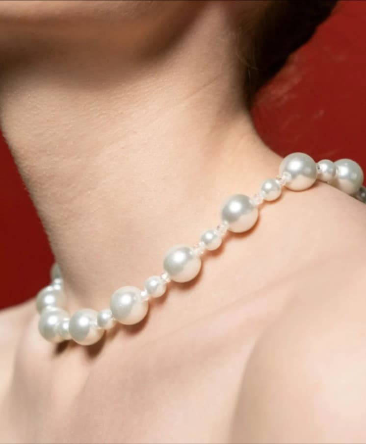 Woman wearing a white pearl necklace; Jewelry sales and repair service.
