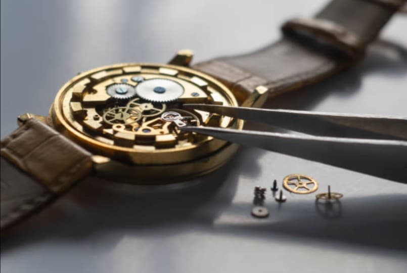 Gold watch repair: close up of watch mechanism being fixed.